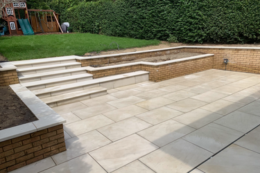 Paved outdoor area Paved outdoor area with steps, surrounded by grass and low walls.
