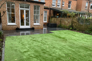 garden area A garden area with artificial grass and a brick house in the background.
