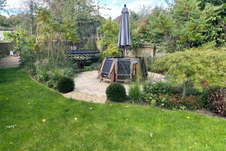 A landscaped garden featuring a patio A landscaped garden featuring a patio, seating area, and greenery.