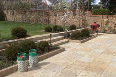 Garden area with stone steps Garden area with stone steps, trimmed bushes, and two green bins.