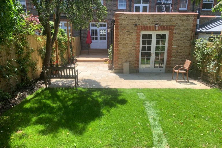 green grass & stone patio A well-maintained garden with green grass, stone patio, and wooden benches.